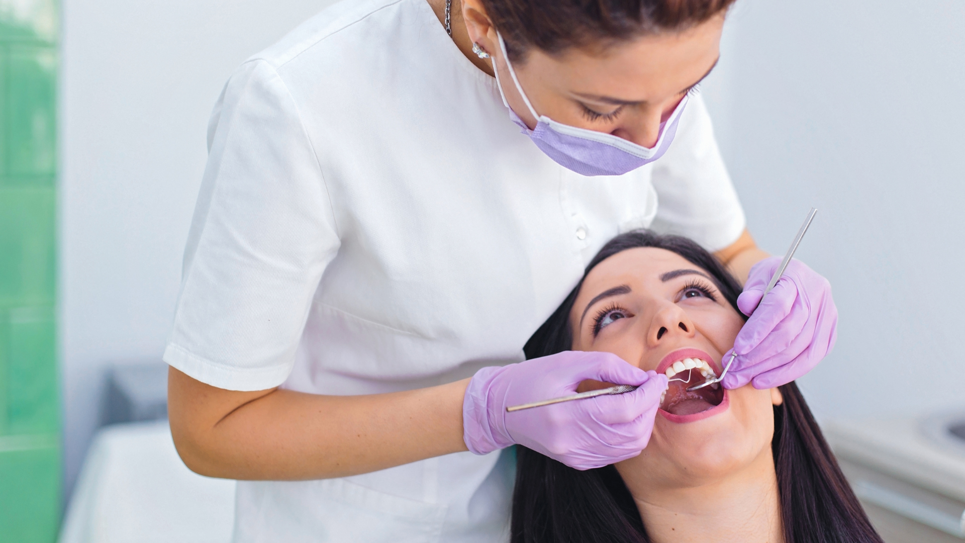 A woman is getting her teeth examined by a dentist.