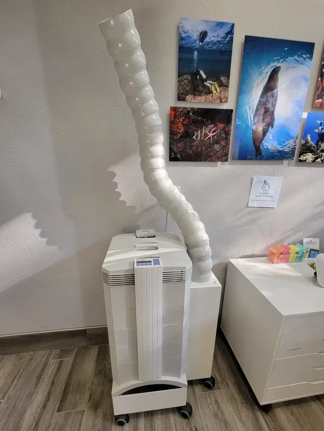 A machine with a long hose attached to it is sitting in a room.