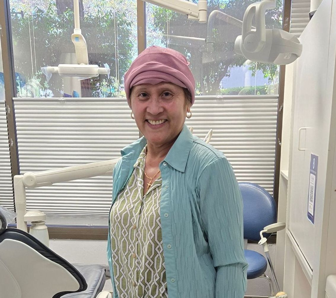 A woman wearing a pink hat is standing in a dental office.