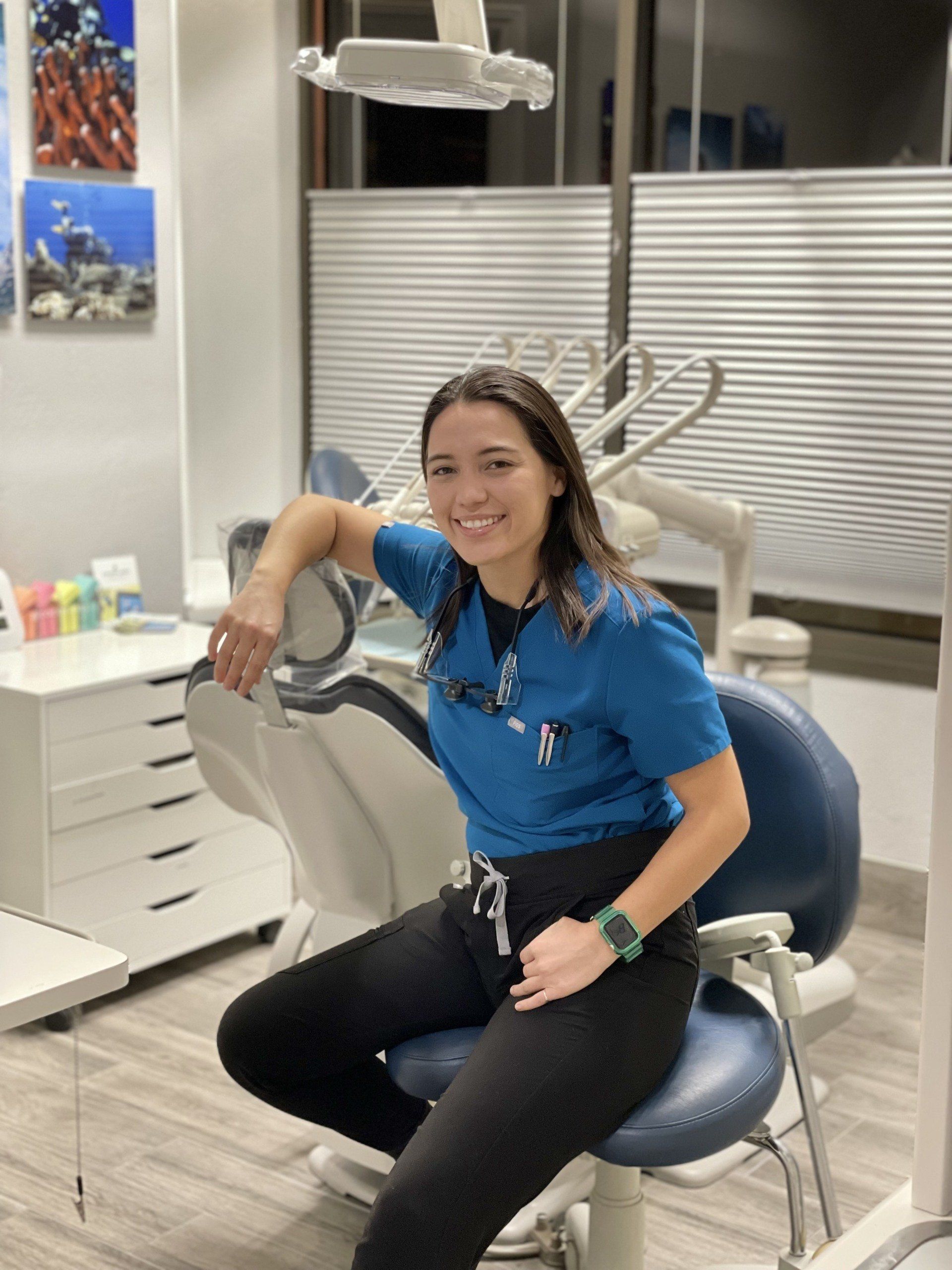 A woman is sitting in a dental chair in a dental office.