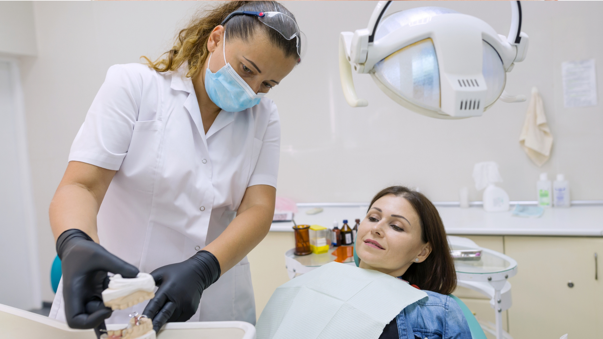 Dentist treating a relaxed patient in a bright dental clinic, with examination light and tools nearby.