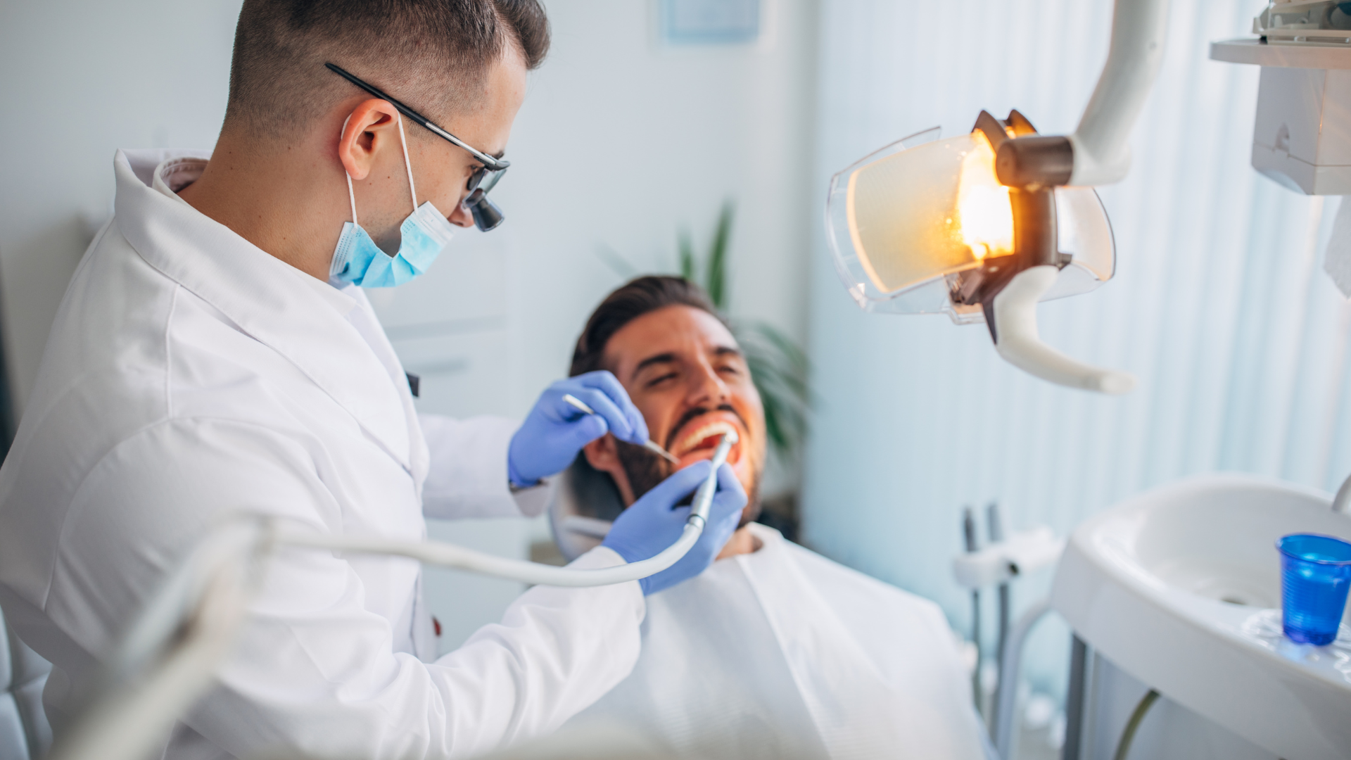 A dentist is examining a man 's teeth in a dental office.