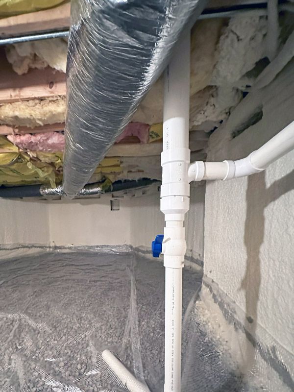 A basement with a lot of pipes and insulation on the ceiling.