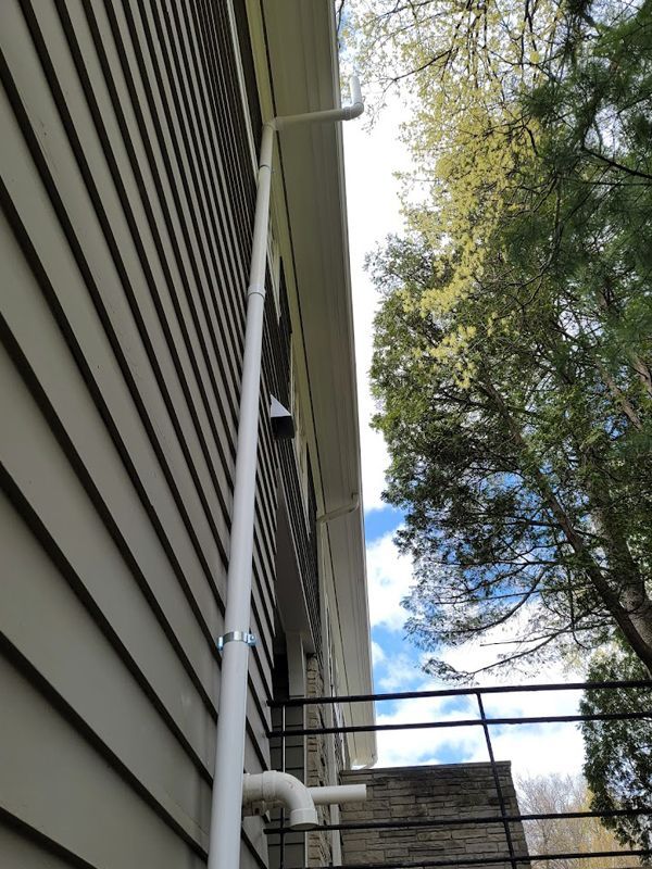 A white pipe is attached to the side of a house.