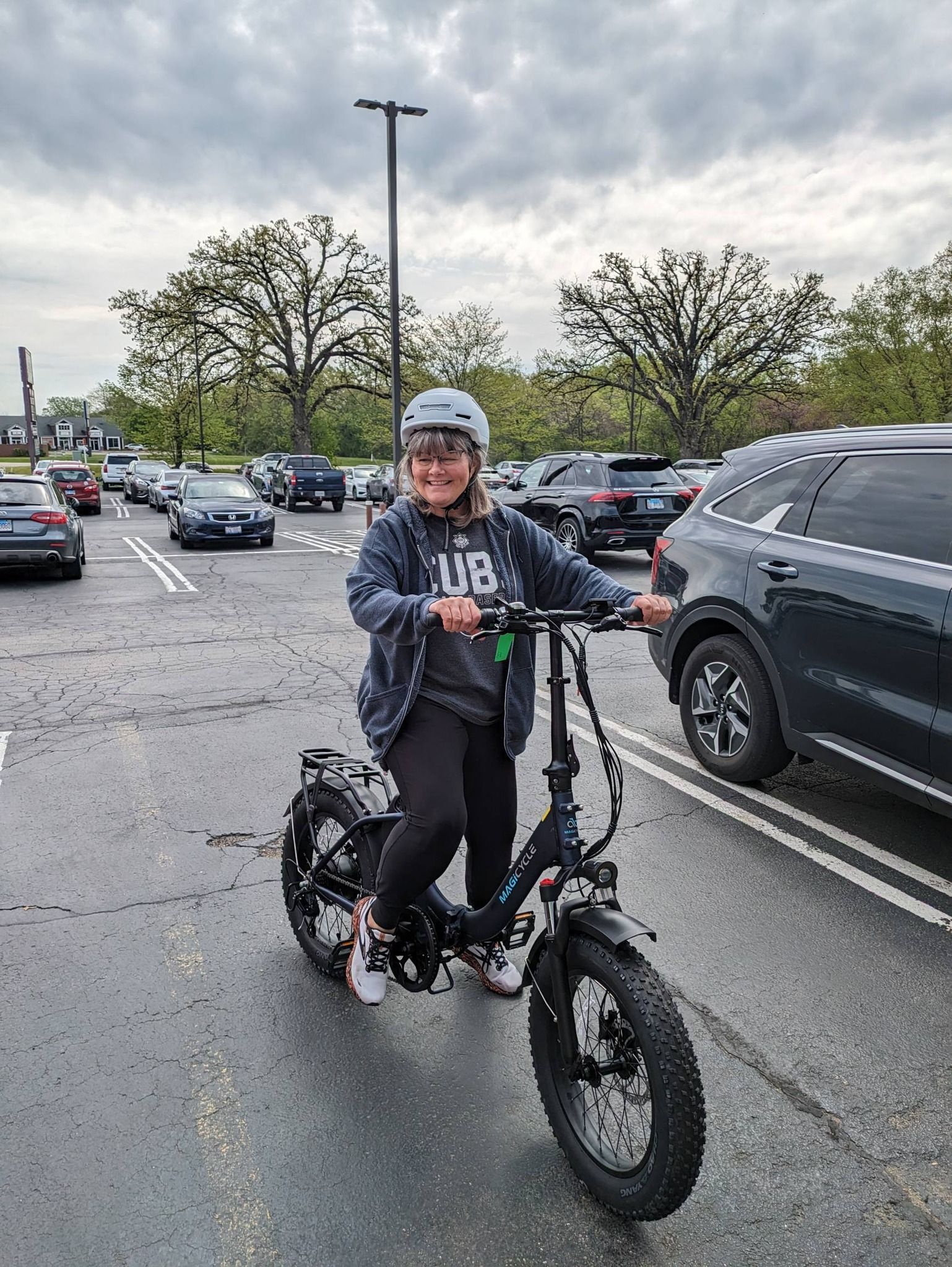 Person riding a fat-tire bike in a wet parking lot under cloudy skies