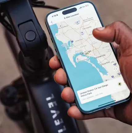 Hand holding a smartphone with a map app next to a black device with a dial.