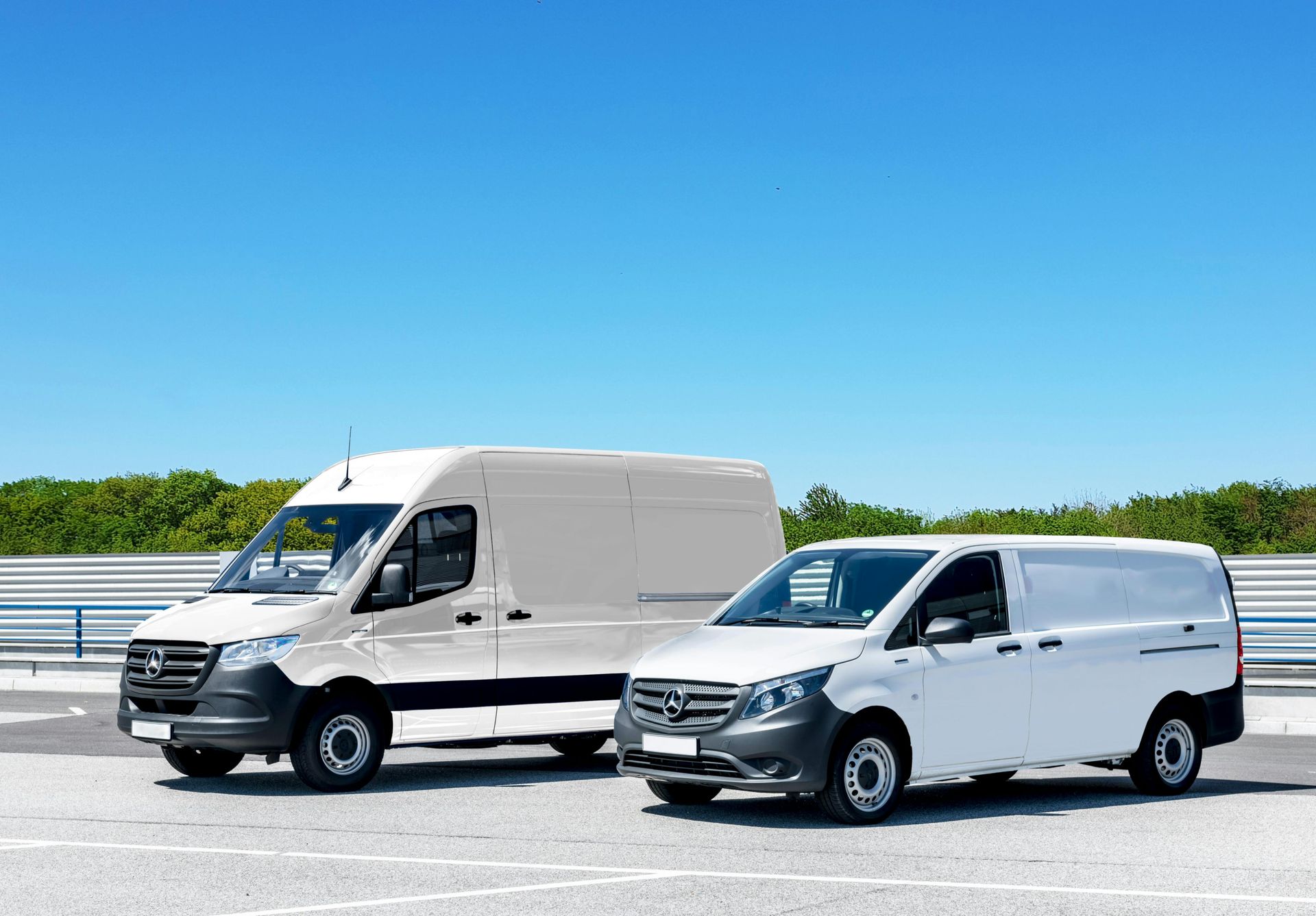 Two white vans that are part of a fleet of vehicles.