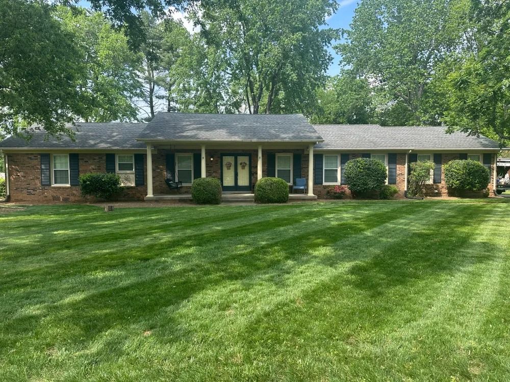 Brick house with a green lawn, trimmed with stripes.