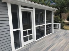 Screened porch with white trim and door, gray siding, and deck.