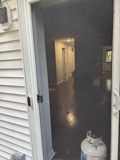 Screen door open to an interior hallway. A propane tank sits inside the door.