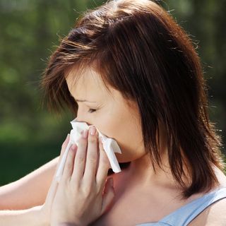 Woman sneezing into tissue