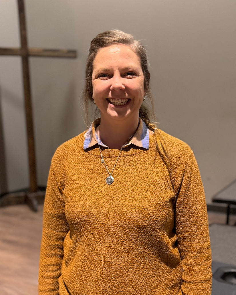 A woman in a pink shirt is looking at the camera.