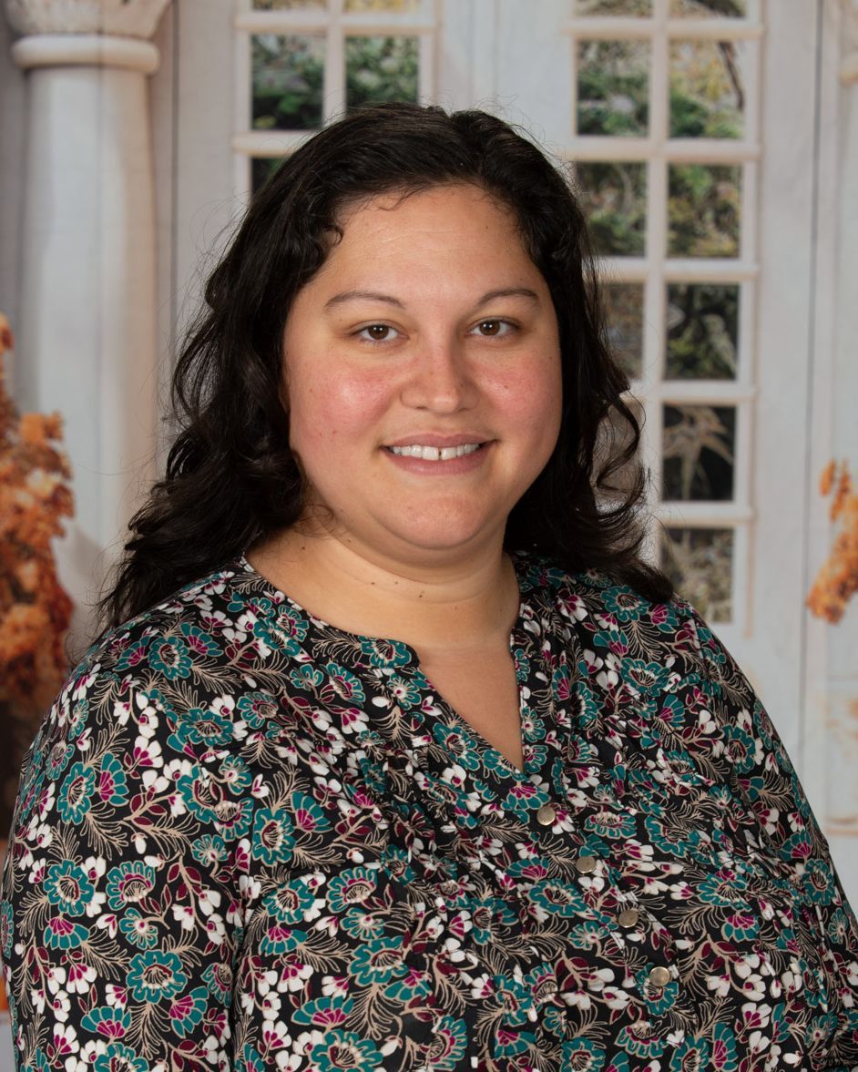 A woman in a red and white floral shirt is smiling