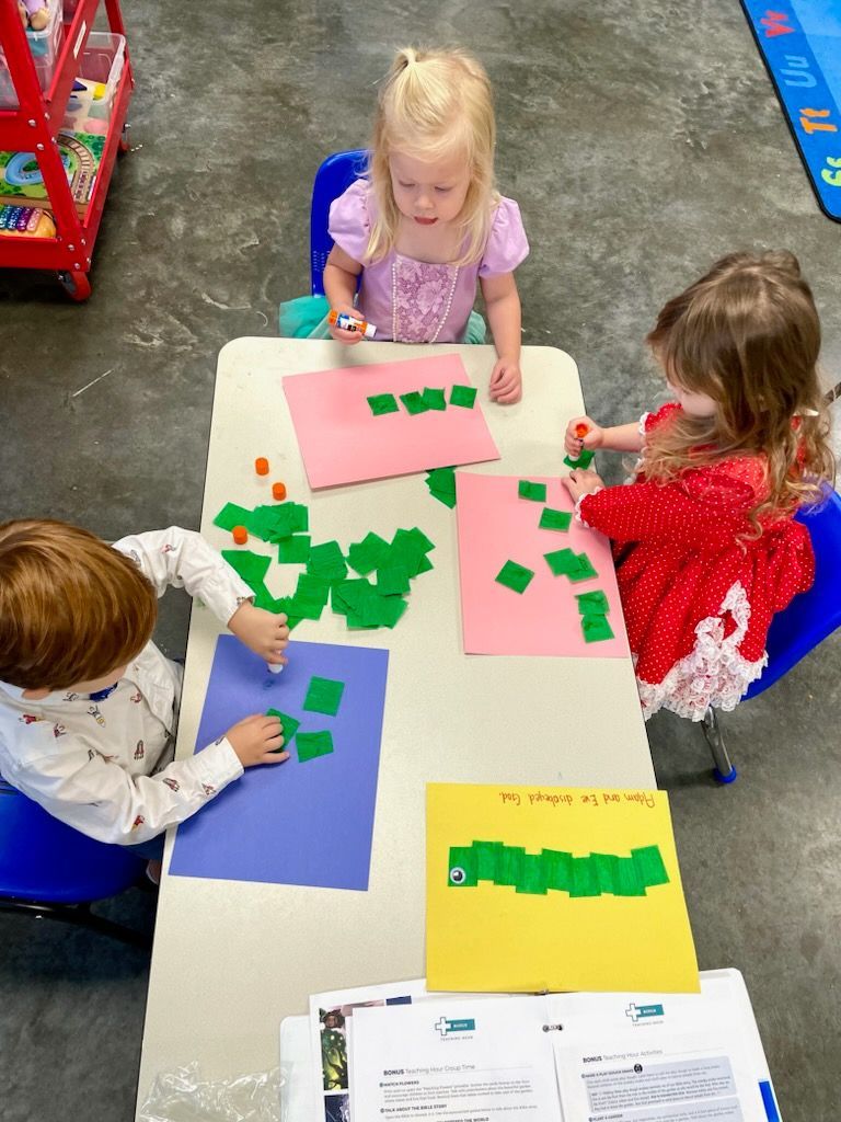 A group of children are sitting at a table making crafts.