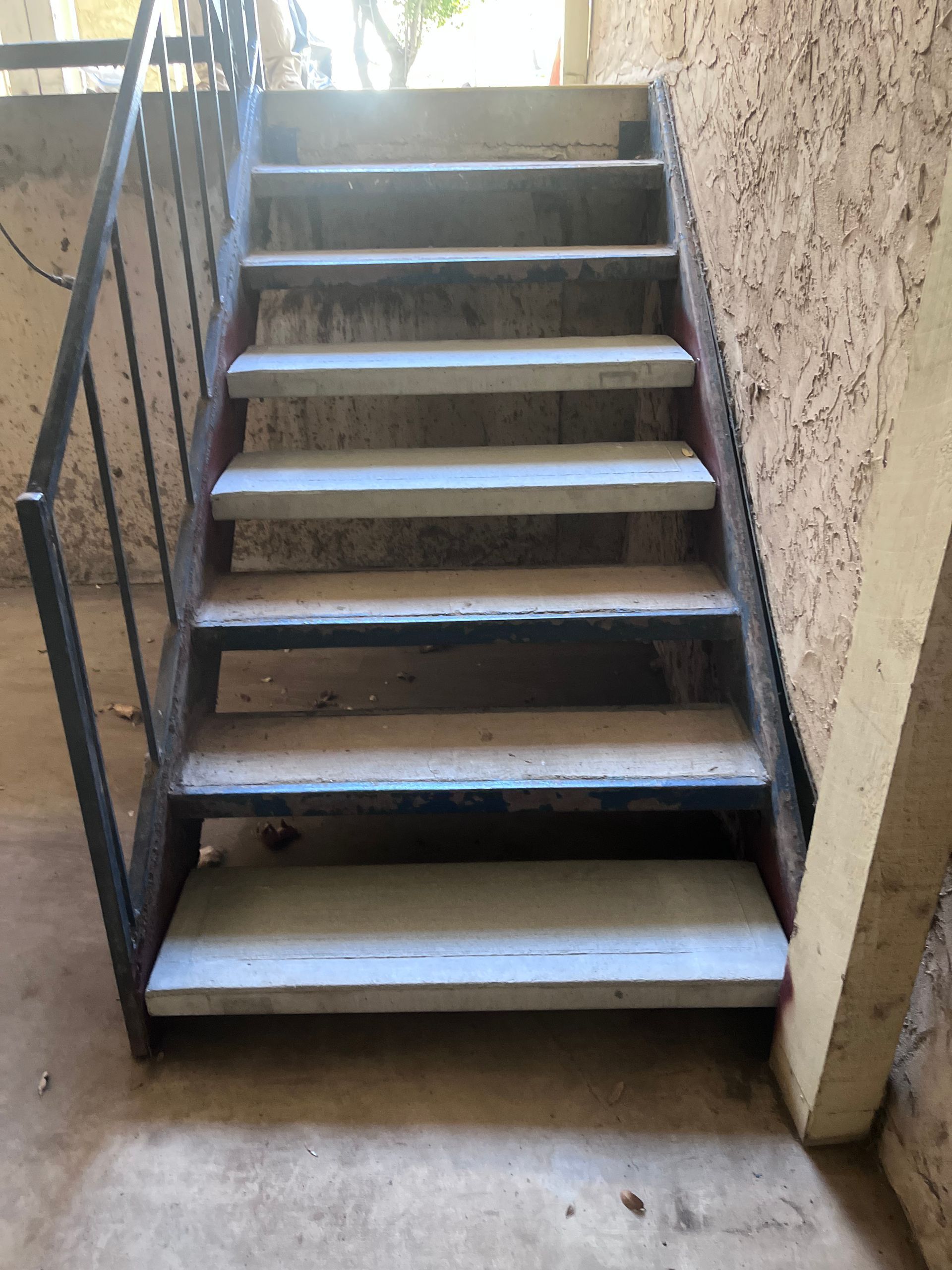 A set of stairs in a building with a metal railing.