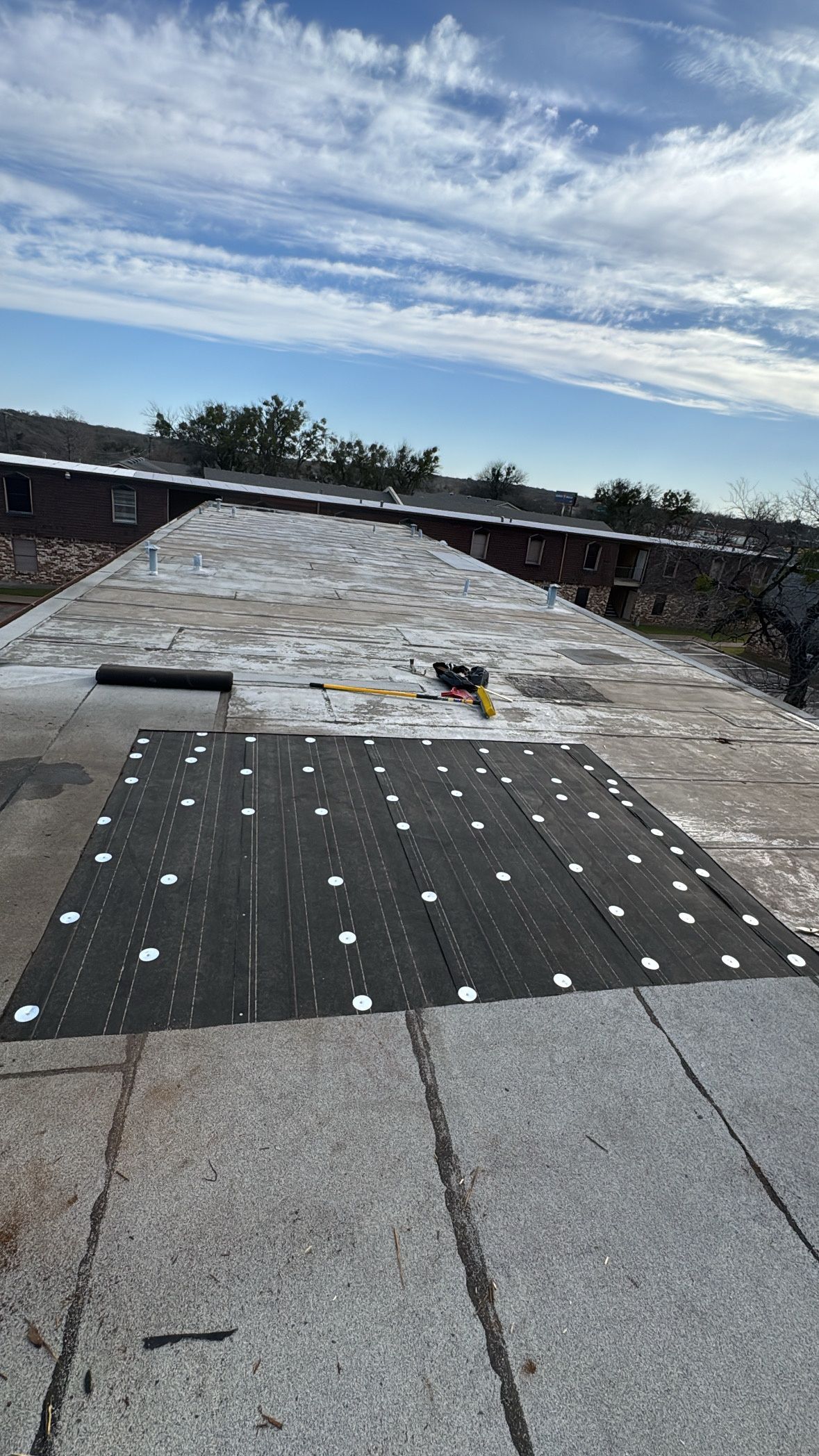 A roof is being repaired on a sunny day with a blue sky in the background.