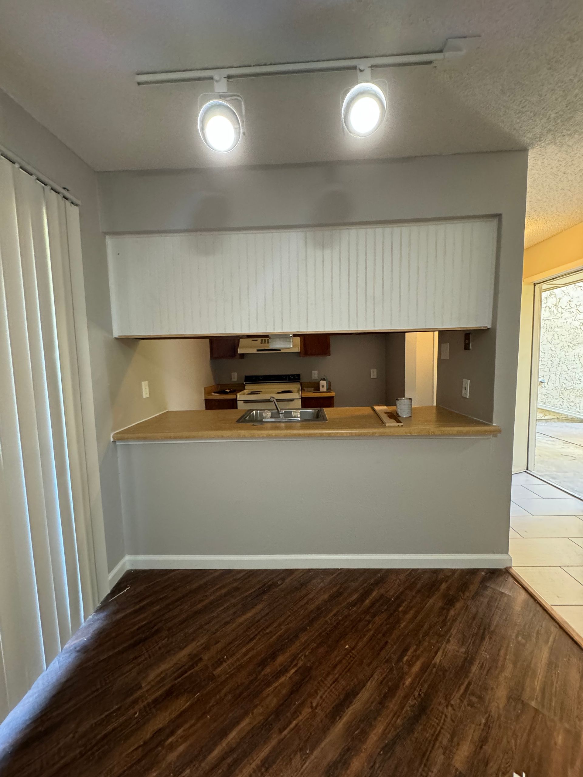 An empty kitchen with hardwood floors and a stove.