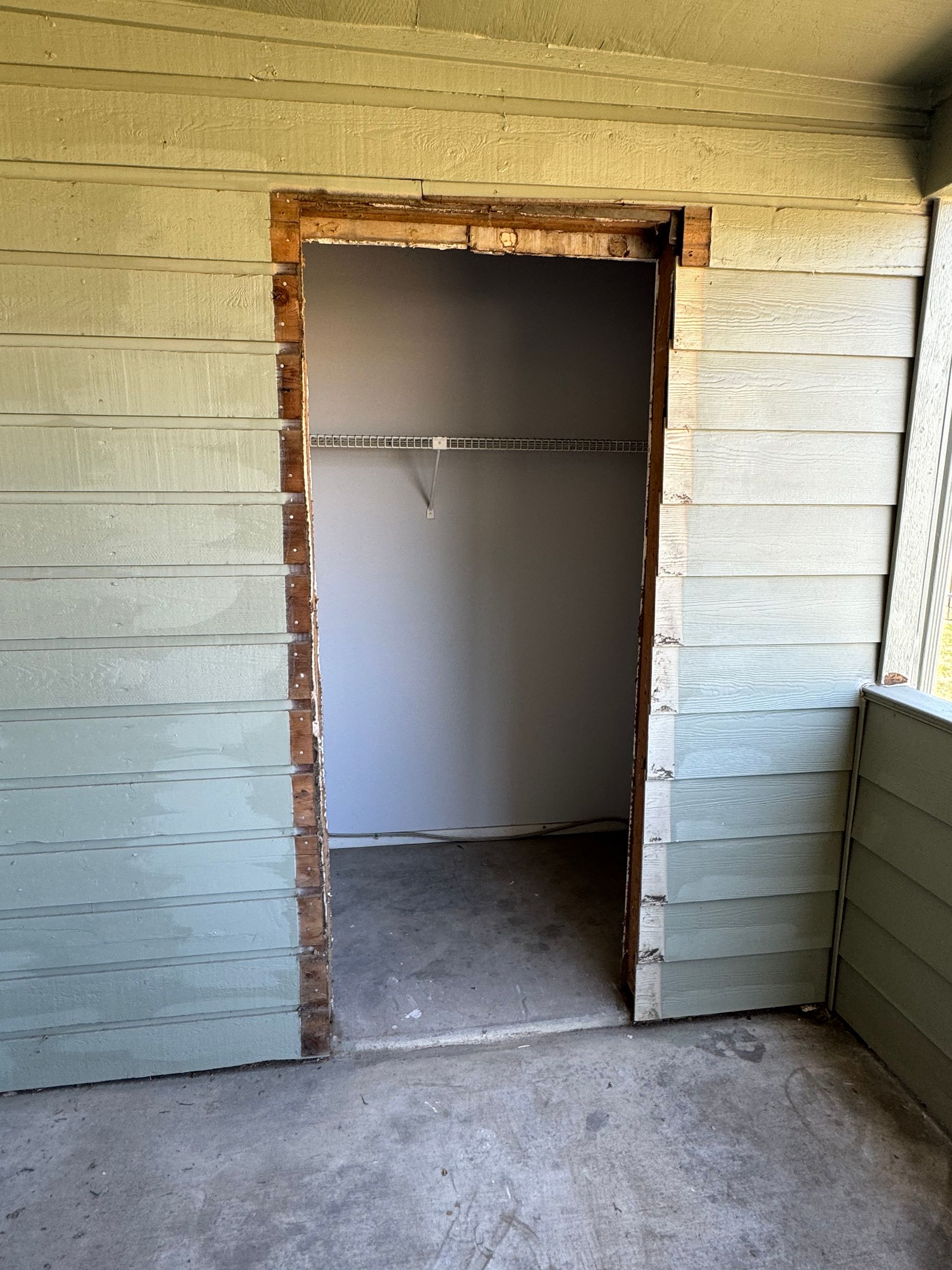 An empty room with a door between two walls and a window.
