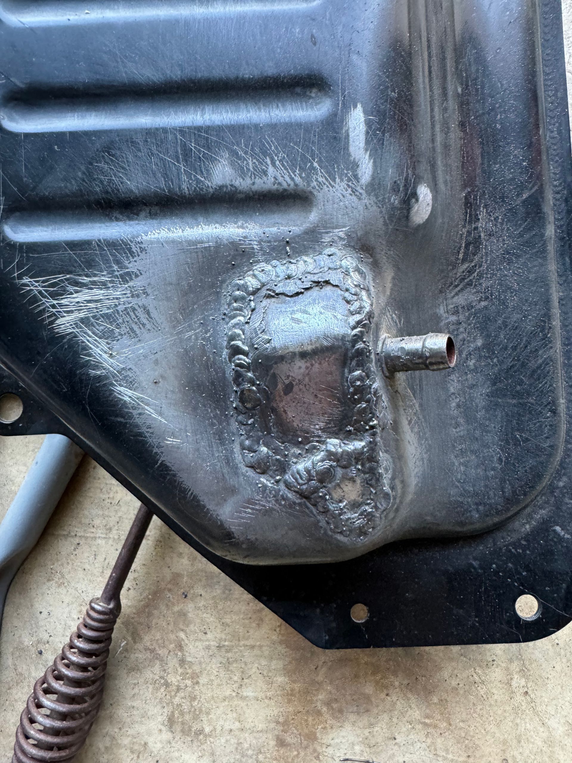A close up of a metal fuel tank with a hole in it.