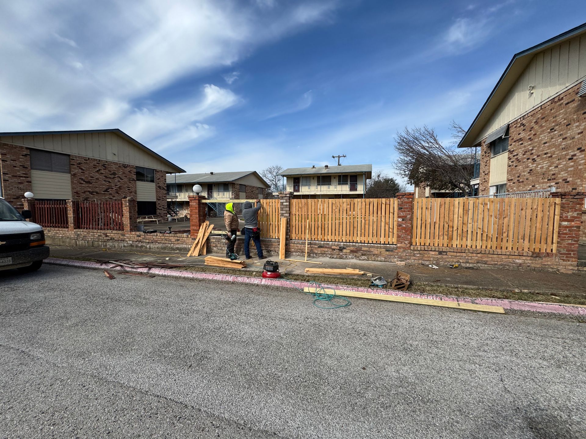 A wooden fence is being built in front of a brick building.