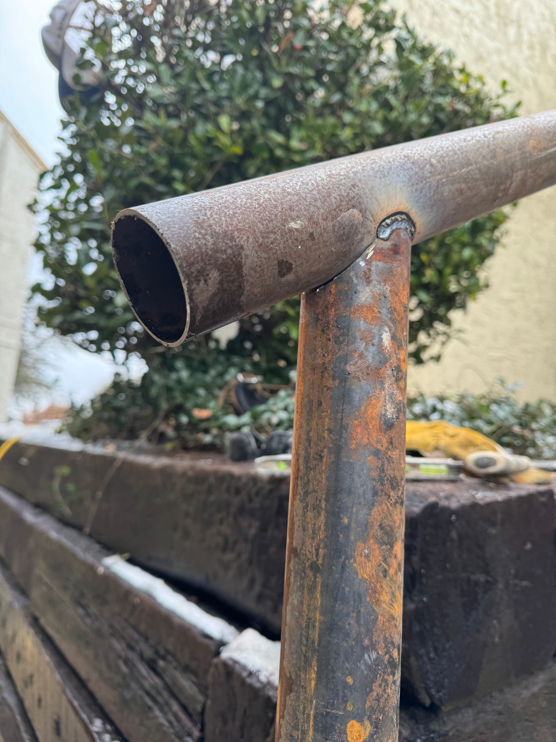 A rusty metal pipe is sitting on top of a wooden planter.