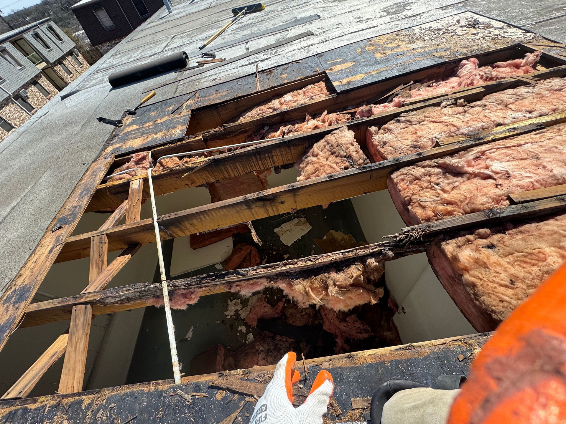 A person is measuring a hole in the roof of a building.