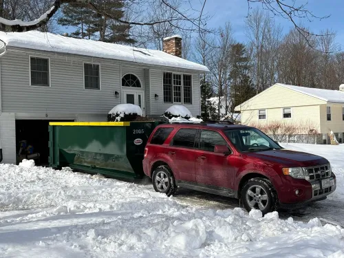 A red suv is parked in the snow in front of a house.