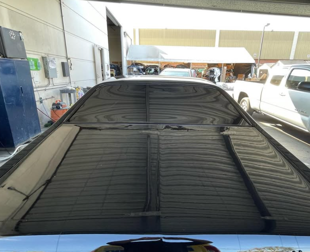 A car with a black roof is parked in a garage.