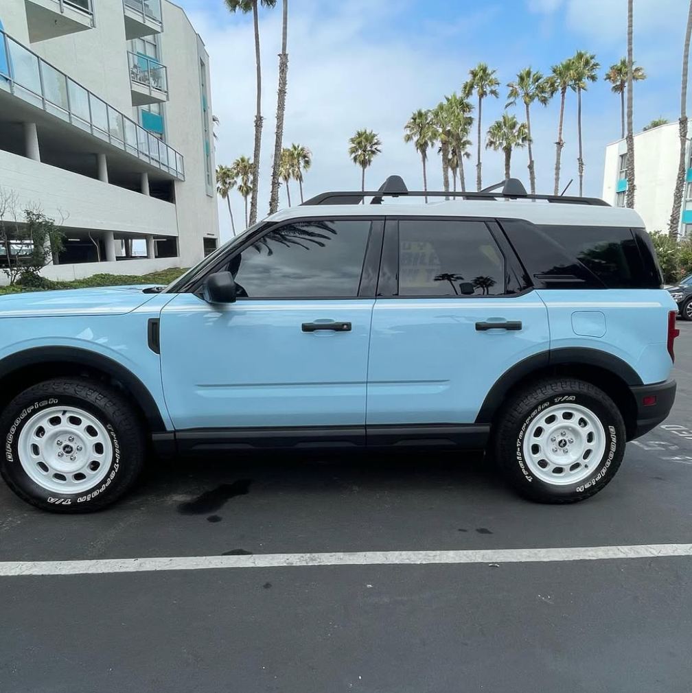 A blue suv is parked in a parking lot with palm trees in the background