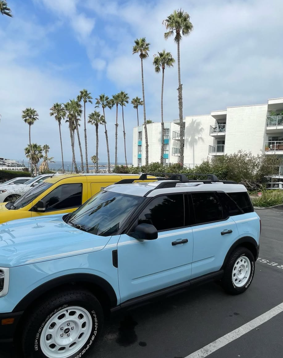 A blue suv is parked next to a yellow suv in a parking lot.