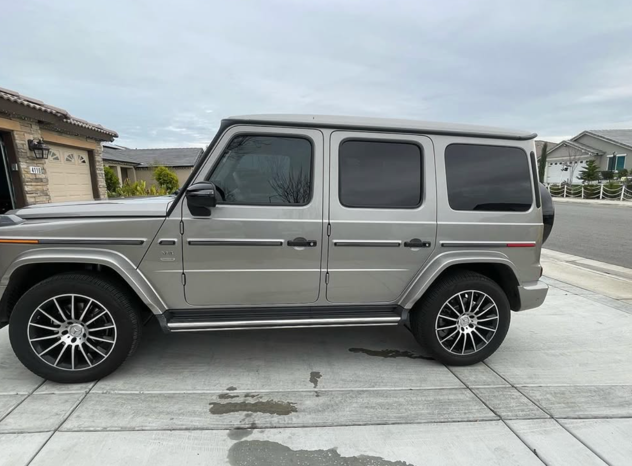 A mercedes benz g63 is parked in a driveway in front of a house.