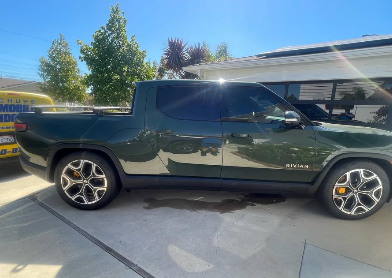 A green truck is parked in a driveway in front of a house.