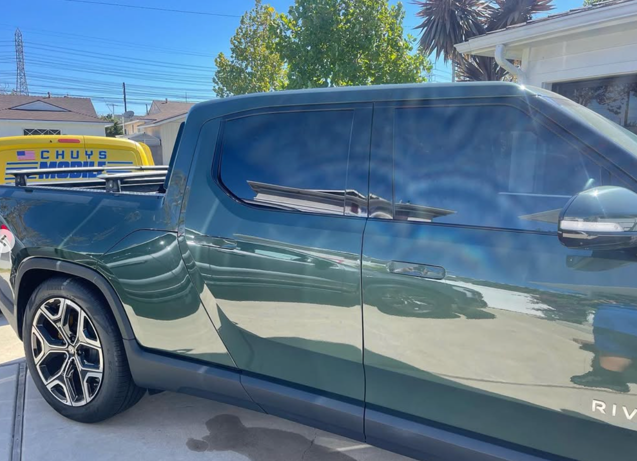 A green truck is parked in front of a house.