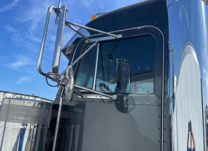 A close up of a truck 's side window with a blue sky in the background.