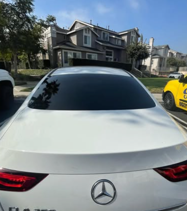 A white mercedes is parked in front of a house