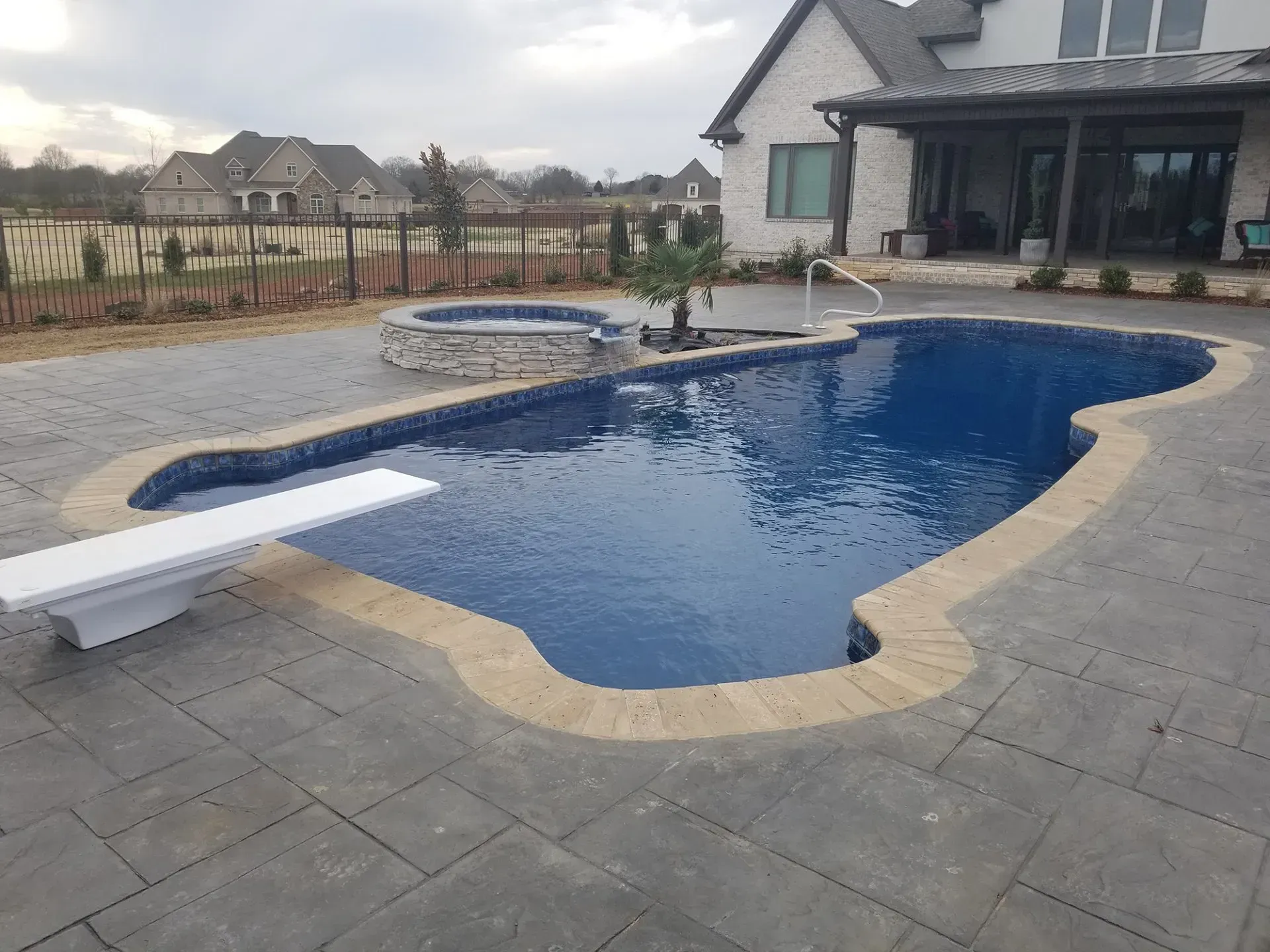 A large swimming pool is sitting on top of a concrete patio.