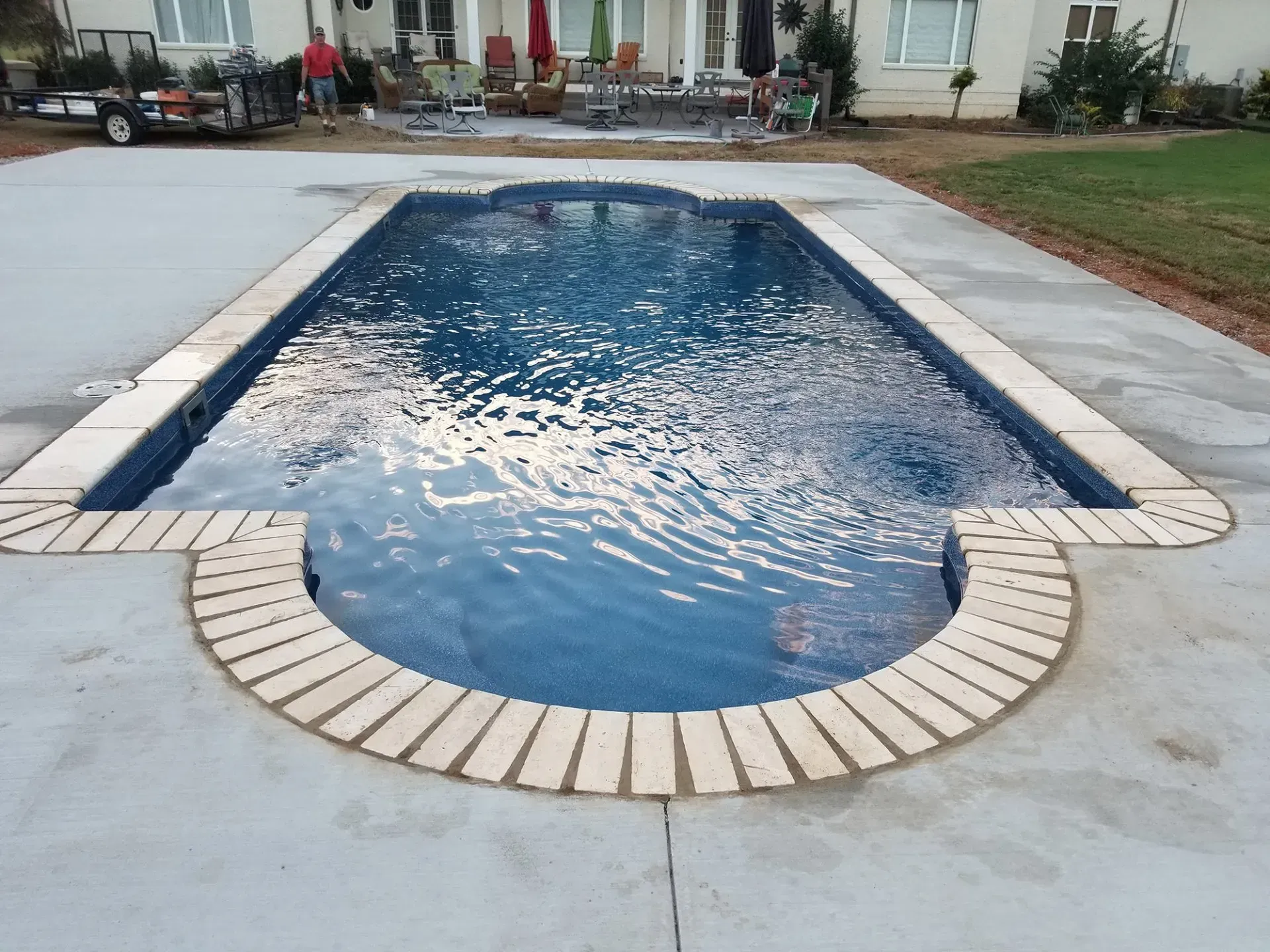 A large swimming pool is surrounded by a concrete patio