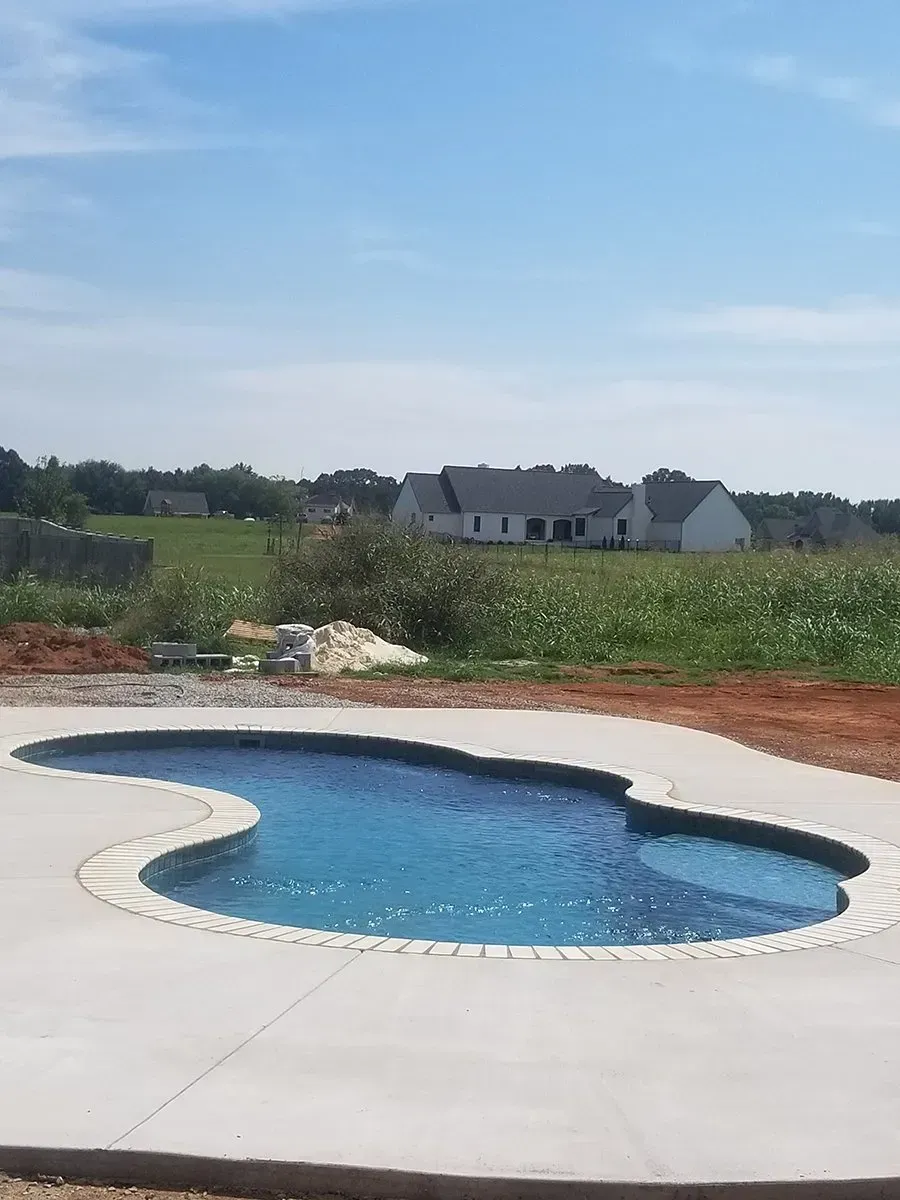 A large swimming pool is surrounded by a concrete patio.