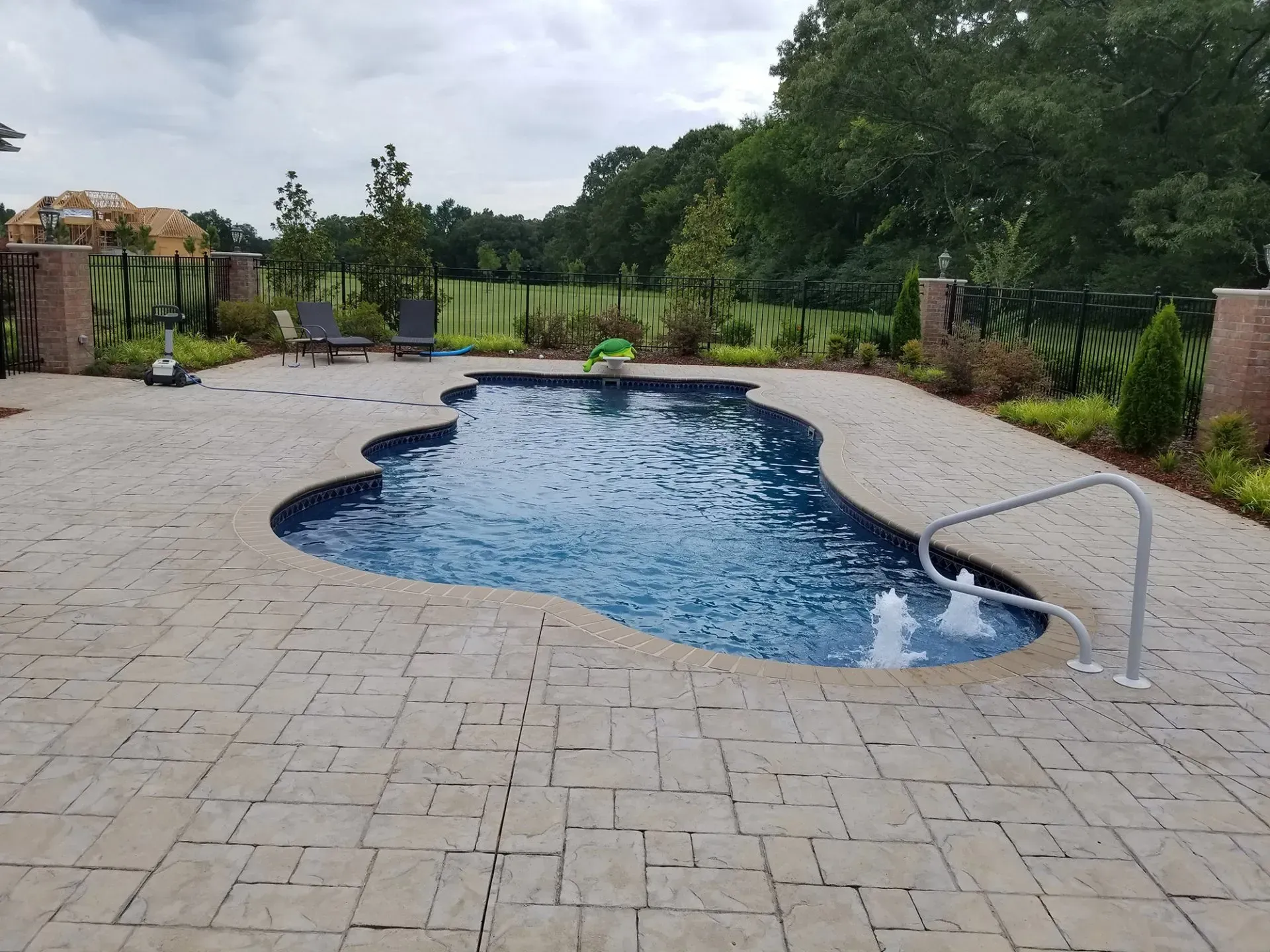A large swimming pool is surrounded by a brick patio