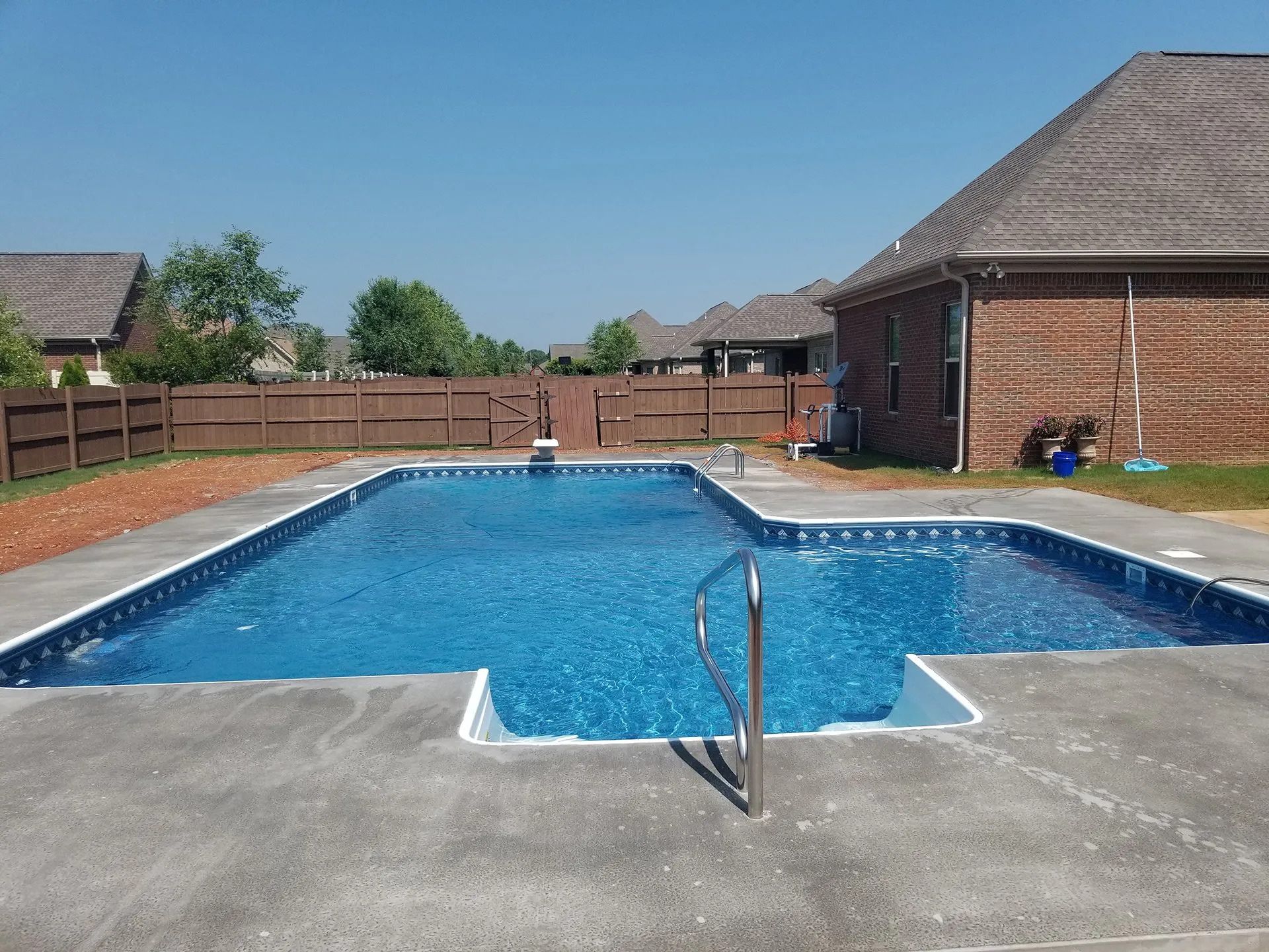 A large swimming pool in front of a brick house