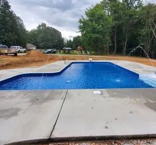 A large swimming pool is being built in the backyard of a house.