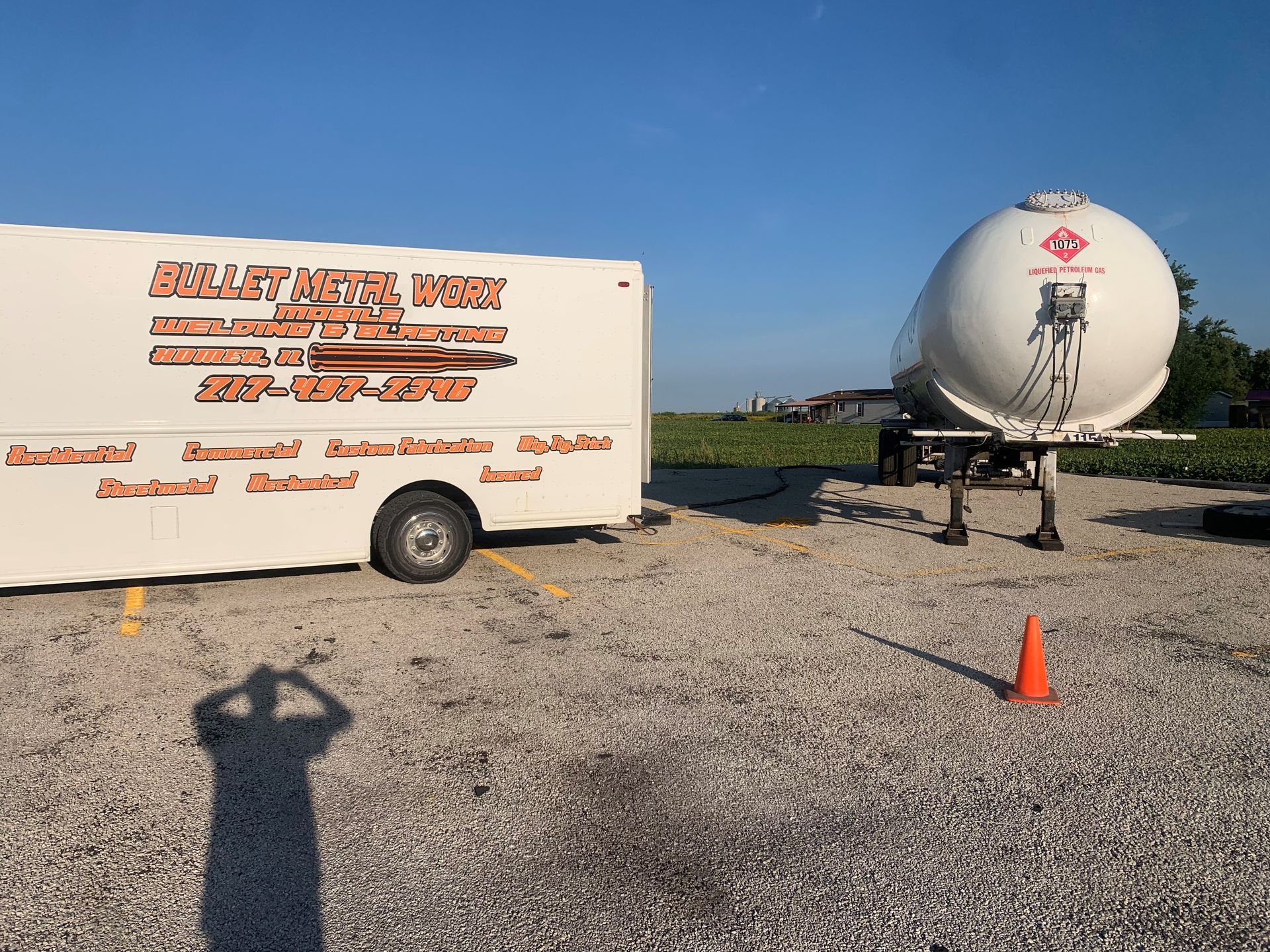 A white trailer is parked next to a large white tank.