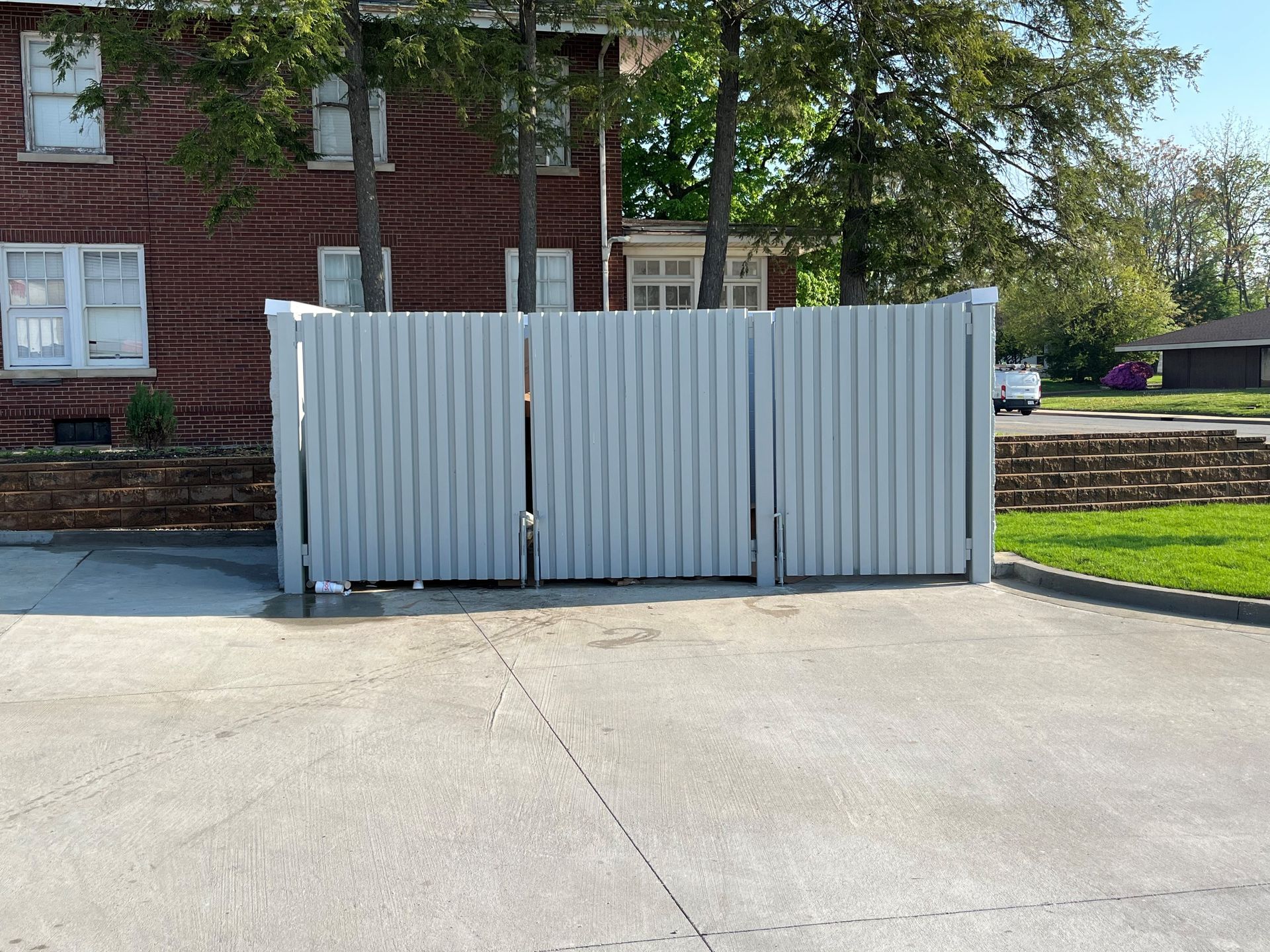 A white fence is in front of a brick building
