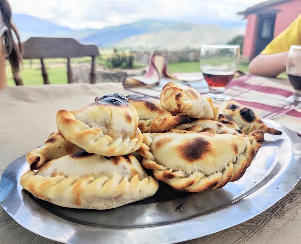Pila de empanadas horneadas sobre una bandeja de metal, con un fondo exterior borroso.