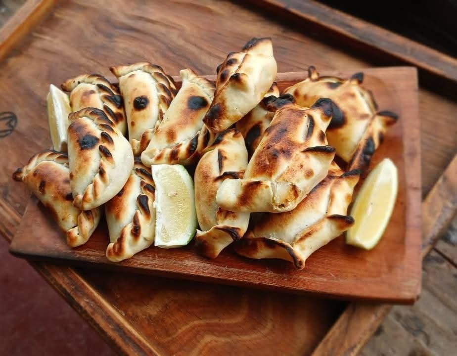 Pila de empanadas horneadas sobre una bandeja de metal, con un fondo exterior borroso.
