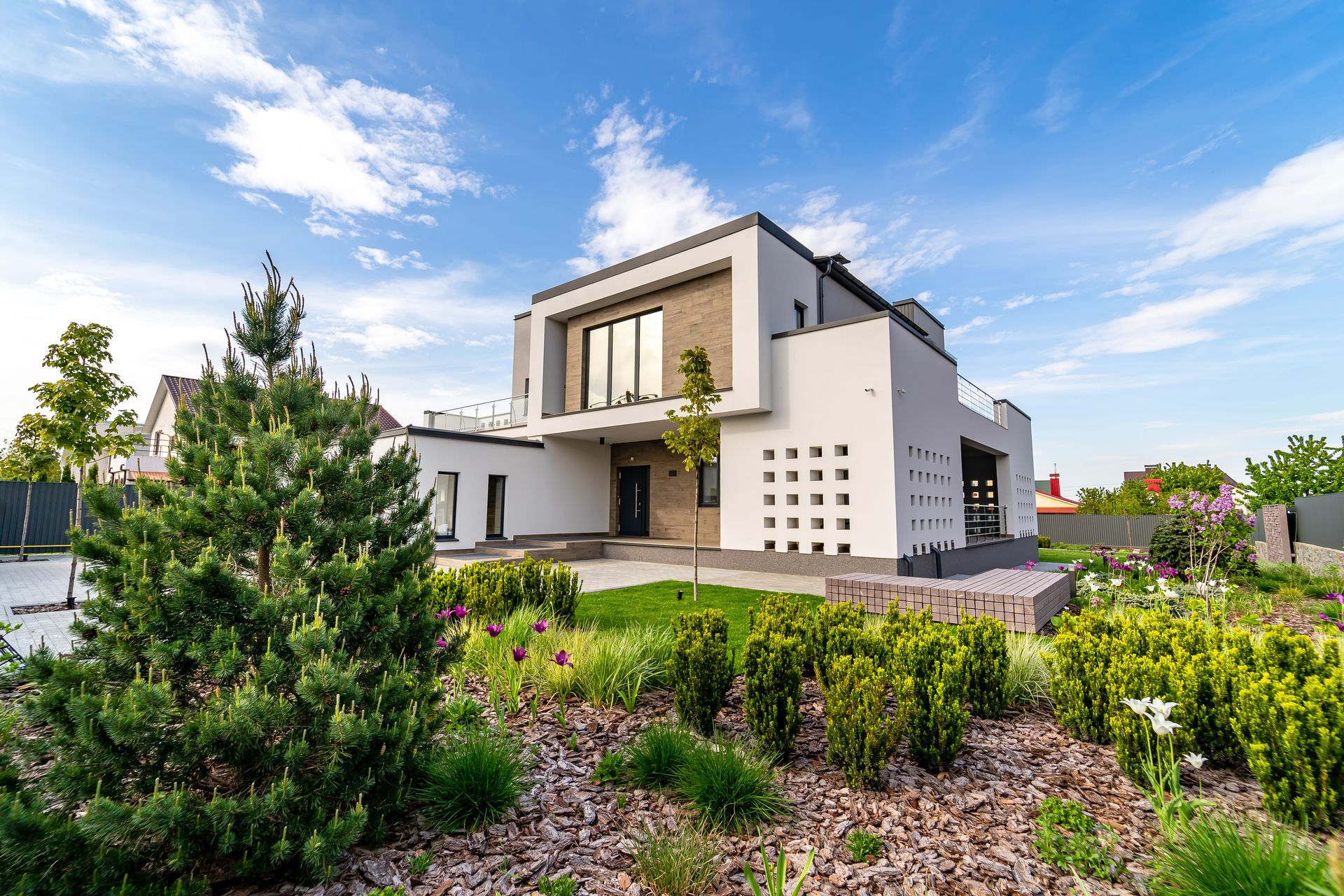 Modern white house with a brick accent, landscaped yard, and blue sky.