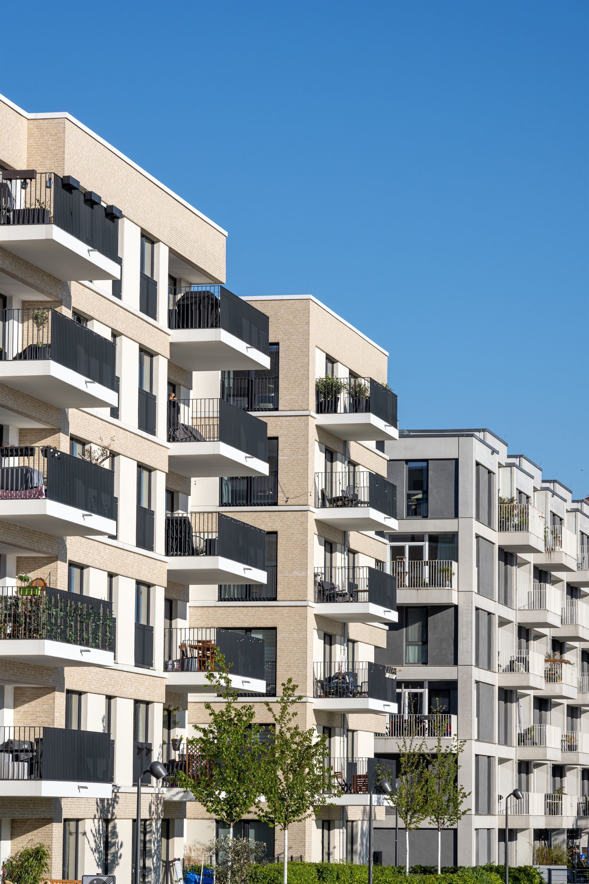 Apartment buildings with balconies against a clear blue sky.