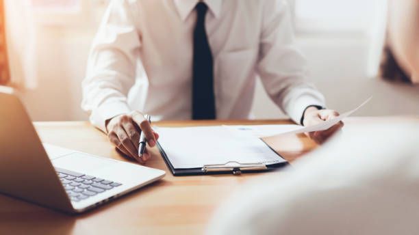 Office meeting with paperwork, pen and laptop on desk for professional consultation support services.