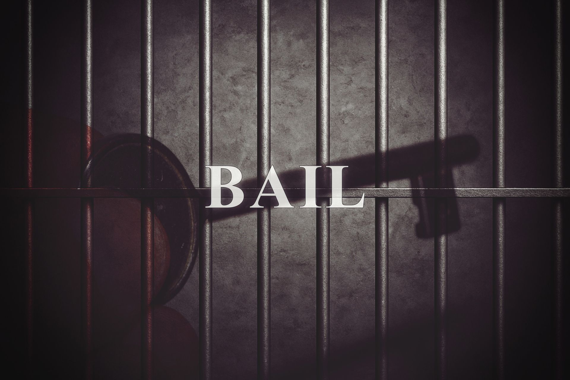 An image of metal jail bars with a key placed in front of them, with the word “bail” over the image.