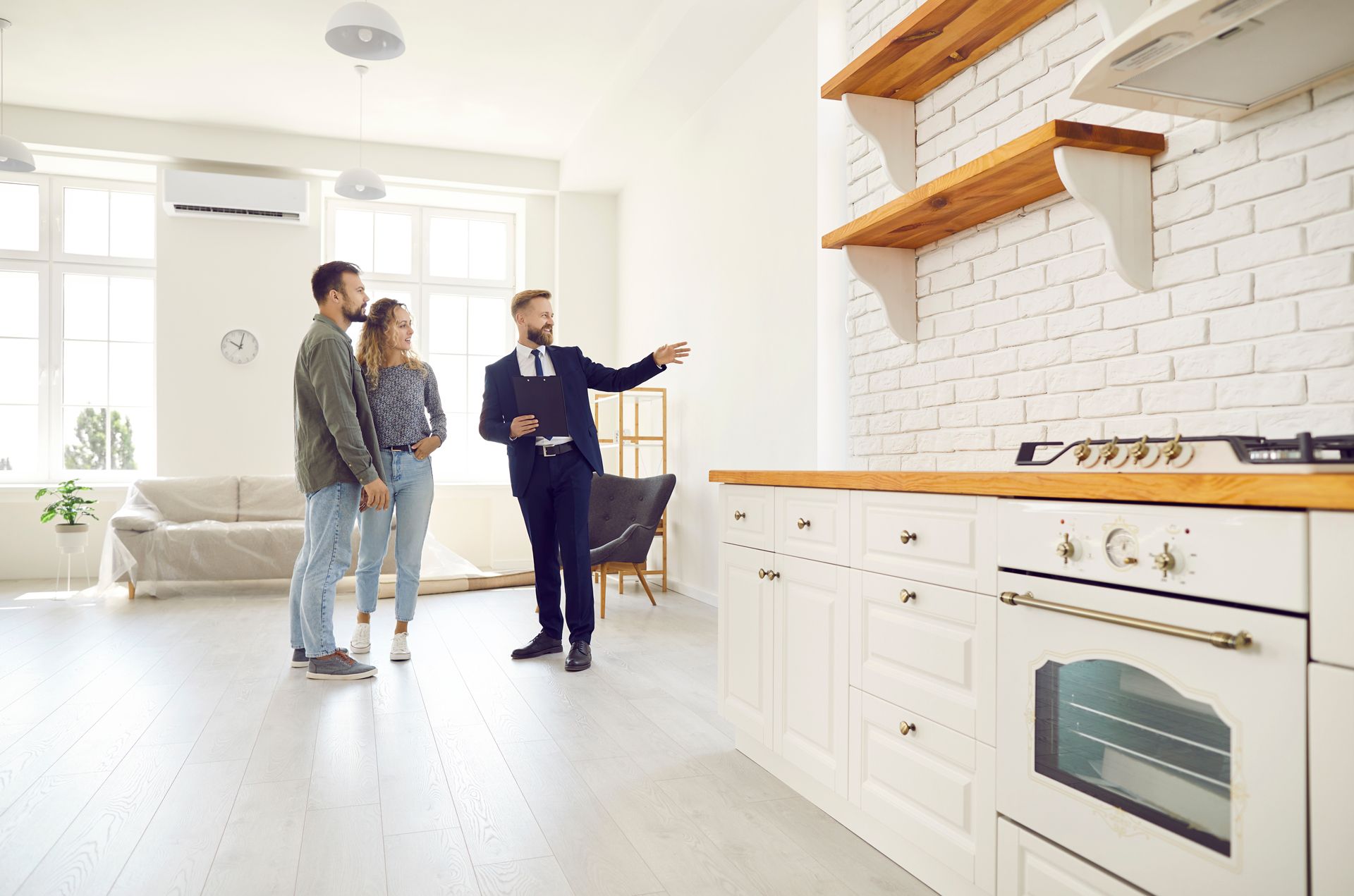 A man is showing a couple a kitchen in a new apartment.